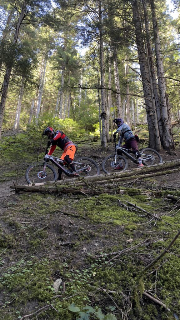 Dos riders de bicicleta de montaña superando un obstáculo en una ruta de enduro guiada