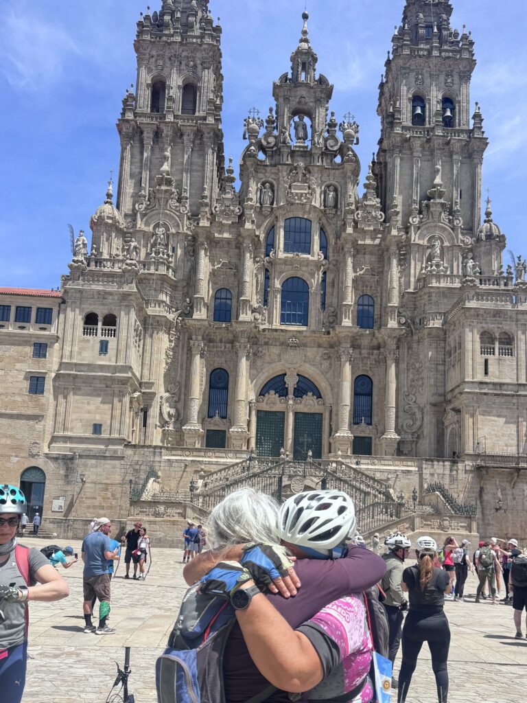 Dos ciclistas se abrazan al llegar a la catedral de Santiago tras hacer el Camino en bicicleta