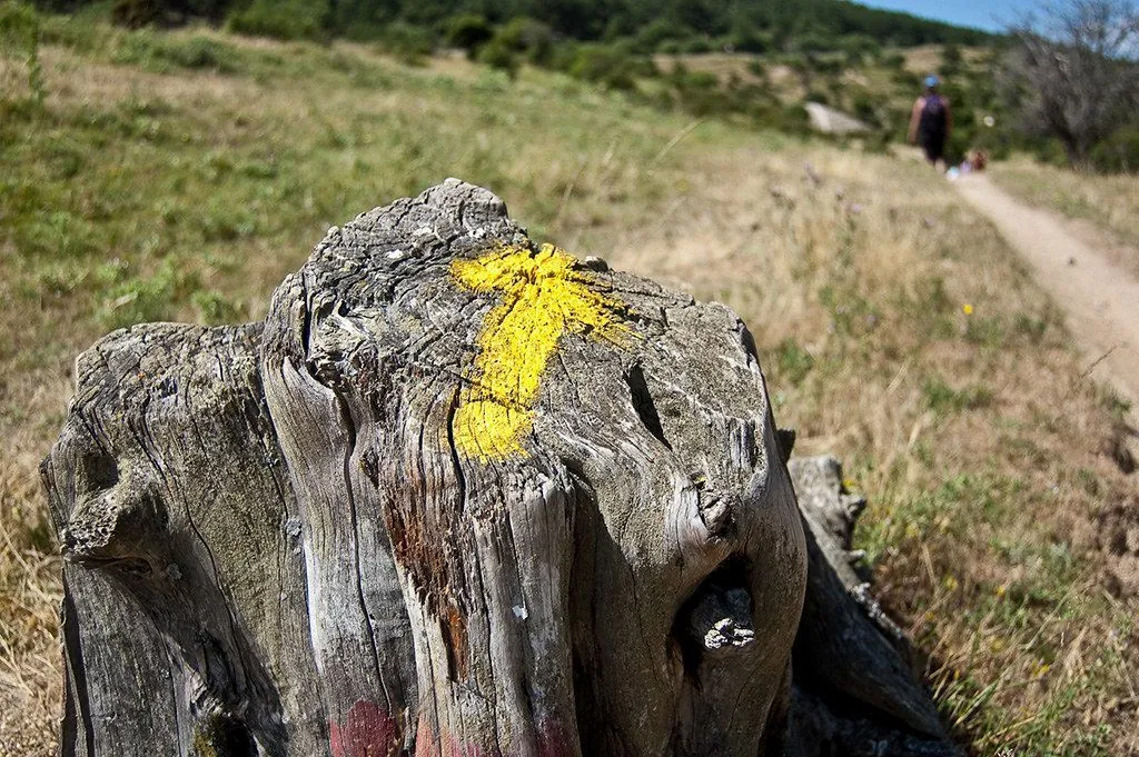 Flecha amarilla pintada en un mojón que señaliza el Camino de Santiago