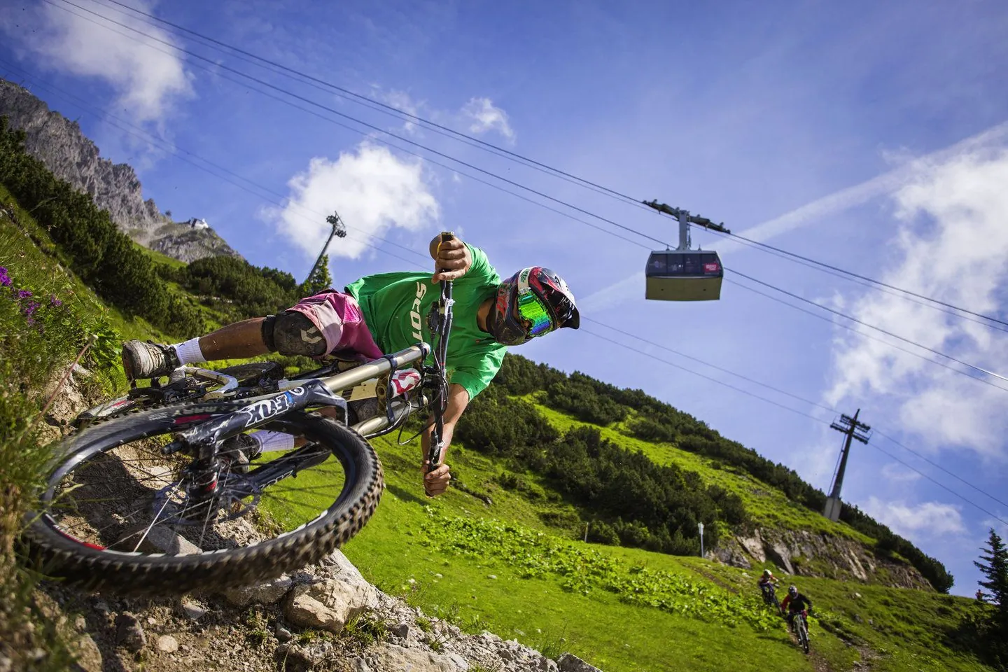 Rider de MTB descendiendo una pista del bike park de Portes du Soleil con la telecabina al fondo